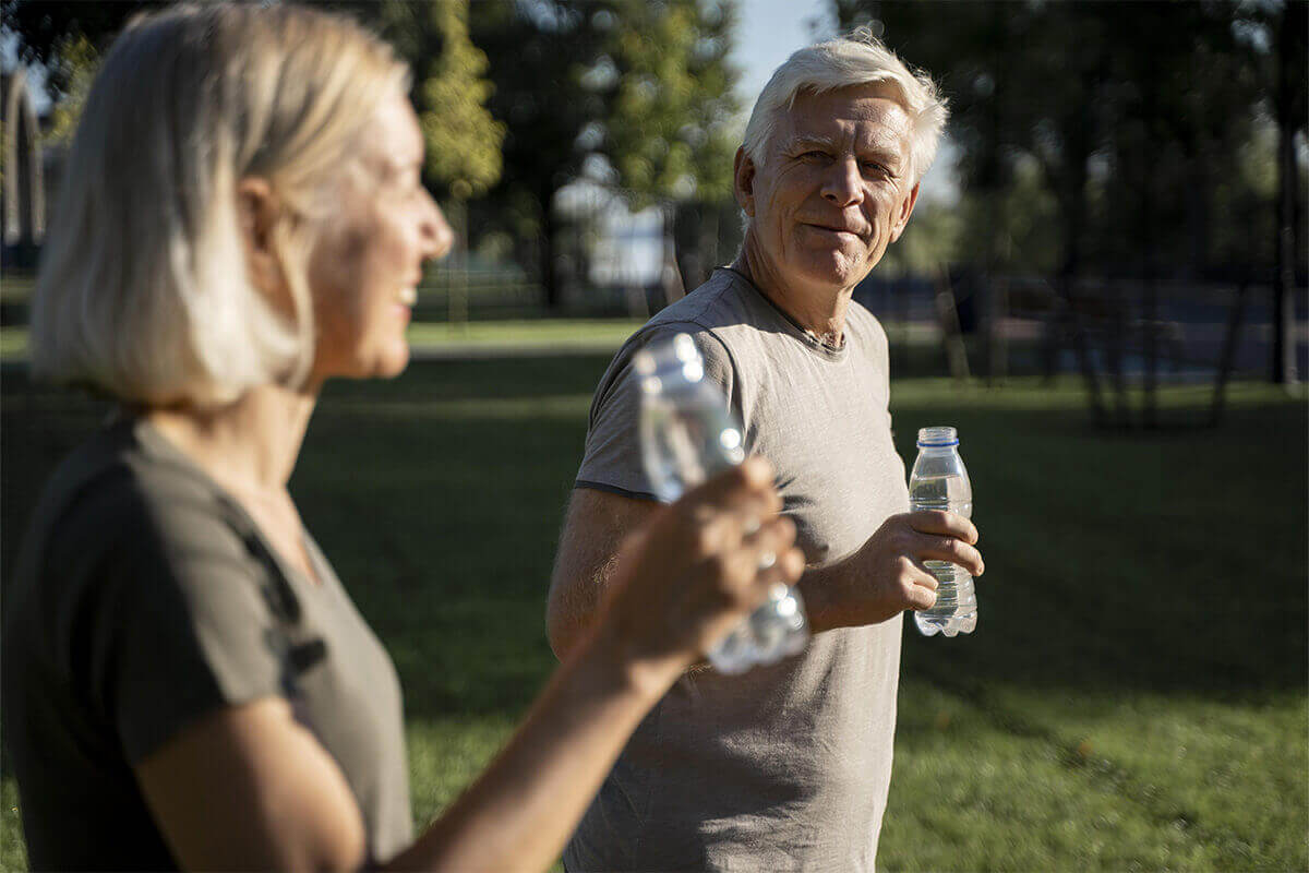 seniors homme et femme buvant une bouteille d'eau